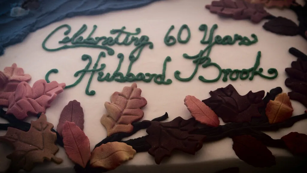 A cake decorated with autumn leaves and green icing that reads 