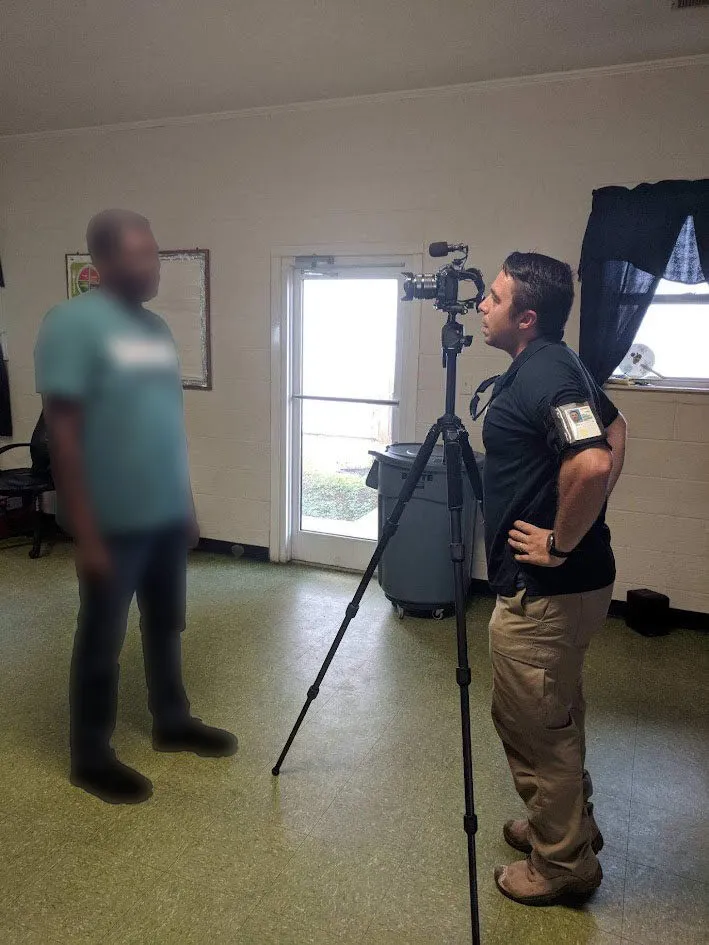 As seen here, an individual in uniform observes a camera setup, highlighting preparation steps in a controlled indoor setting.