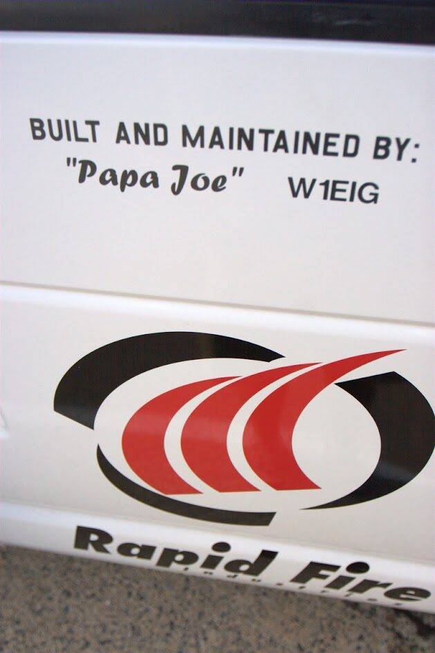 A white surface displays the text "BUILT AND MAINTAINED BY: 'Papa Joe' W1EIG" above a stylized red and black logo and part of the phrase "Rapid Fire" below.
