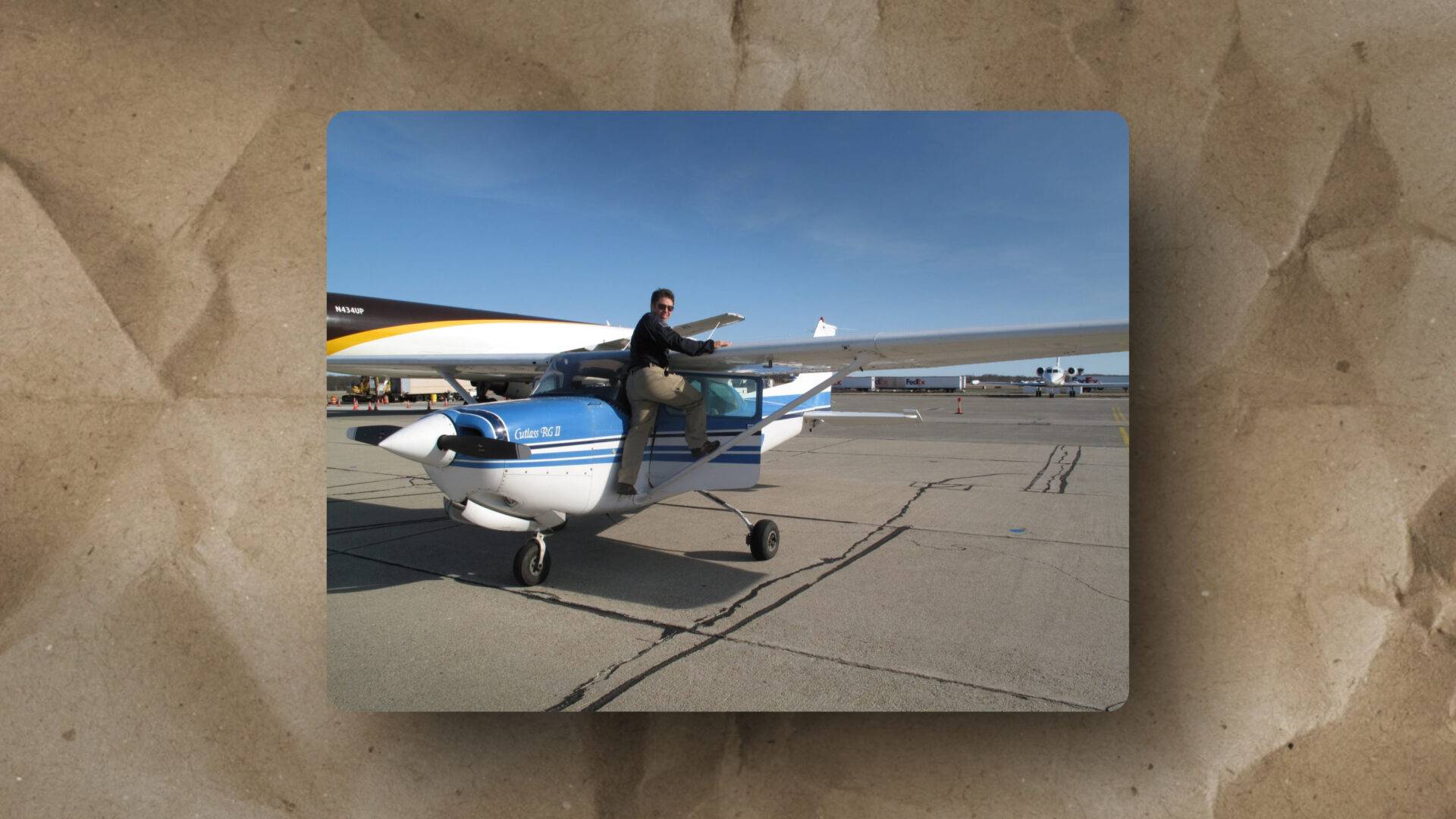This image illustrates aircraft scale and contrast, as seen by a person seated on a small plane’s wing with a larger plane nearby.