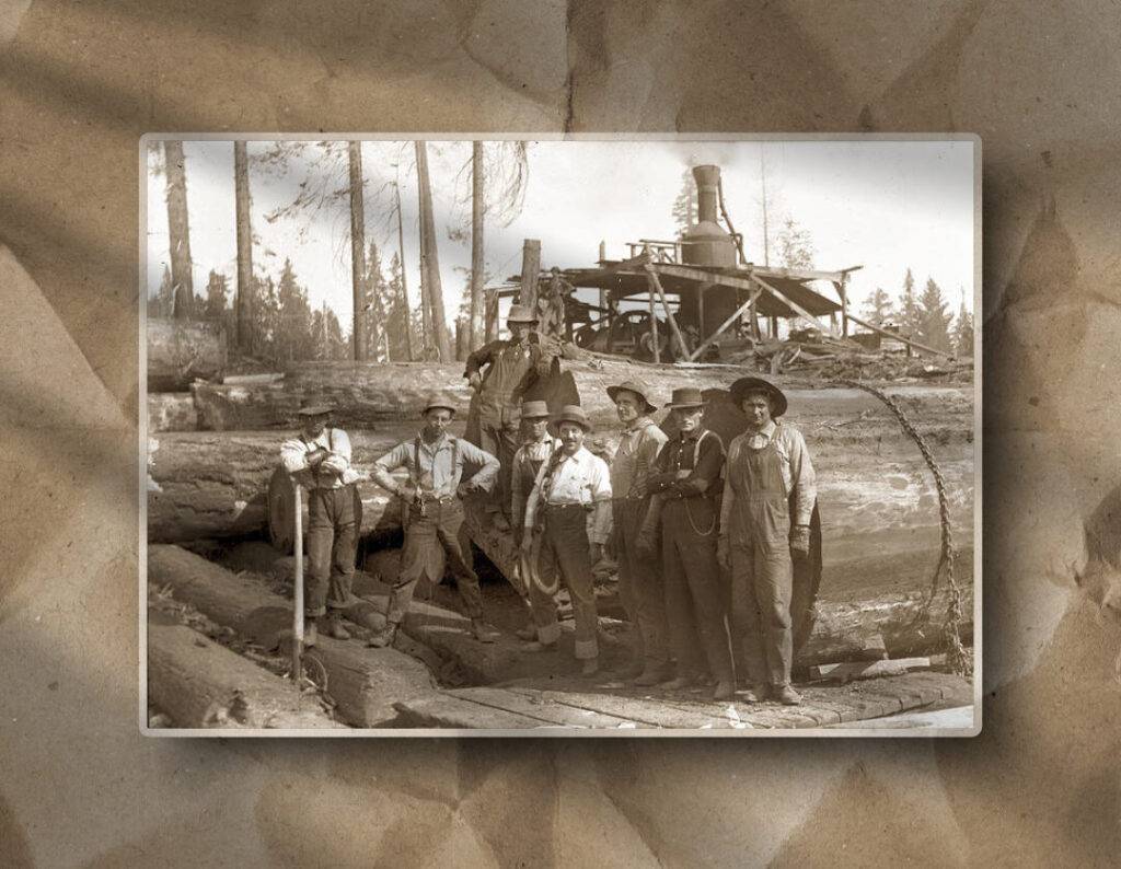 This photo documents early logging practices, with workers, steam machinery, and forest context displayed on crumpled brown paper.